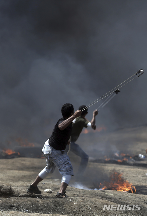 【가자=AP/뉴시스】 14일 가자 지구 팔레스타인 젊은이들이 이스라엘 봉쇄 철조망 앞에서 이스라엘 저격병을 향해 돌팔매 공격에 나서고 있다. 2018. 5. 14. 