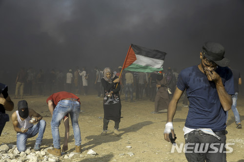 【가자=AP/뉴시스】 한 팔레스타인 여성이 15일(현지시간) 팔레스타인 가자지구에서 팔레스타인 국기를 미국의 대사관 이전에 항의하는 시위를 벌이고 있다. 2018.05.16.