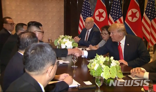 【싱가포르=AP/뉴시스】도널드 트럼프 미국 대통령과 김정은 북한 국무위원장이 12일 싱가포르 카펠라 호텔에서 일대일 회담을 마친 후 확대회의를 시작하기 전 악수를 하고 있다. 사진은 동영상을 캡처한 것이다. 2018.06.12 