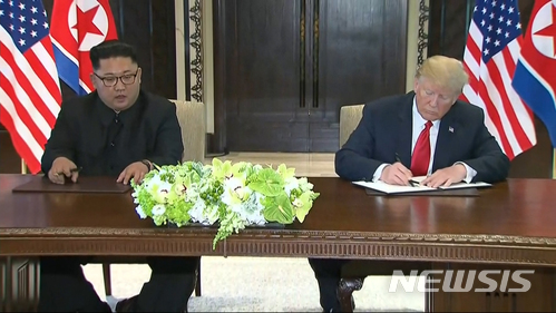 【싱가포르=AP/뉴시스】도널드 트럼프 미국 대통령과 김정은 북한 국무위원장이 12일 싱가포르 센토사 섬 내 카펠라 호텔에서 합의문에 서명하고 있다. 사진은 동영상을 캡처한 것이다. 2018.08.12 