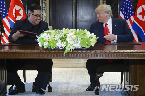 【싱가포르=AP/뉴시스】도널드 트럼프 미국 대통령과 김정은 북한 국무위원장이 12일 싱가포르 센토사 섬 내 카펠라 호텔에서 합의문에 서명한 후 웃고 있다. 2018.08.12
