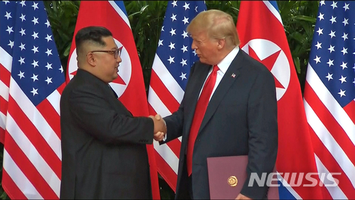 【싱가포르=AP/뉴시스】도널드 트럼프 미국 대통령과 김정은 북한 국무위원장이 12일 싱가포르 센토사 섬 내 카펠라 호텔에서 합의문에 서명한 후 악수하고 있다. 사진은 동영상을 캡처한 것이다. 2018.08.12