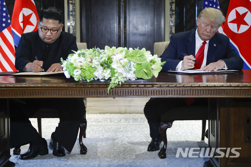【싱가포르=AP/뉴시스】김정은 북한 국무위원장(왼쪽)과 도널드 트럼프 미 대통령이 12일 싱가포르 카펠라 호텔에서 사상 첫 북미 정상회담을 마친 뒤 합의문에 서명하고 있다. 2018.6.12