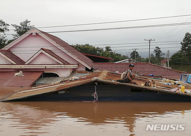 【아타프=AP/뉴시스】라오스 남동부 아타프 주에서 세피안-세남노이 수력발전 댐이 붕괴해 홍수가 발생하자 24일 한 남성이 지붕 위에 올라가 구조를 기다리고 있다. 사진은 현지방송 아타프TV 동영상을 캡처한 것이다. 2018.07.25 