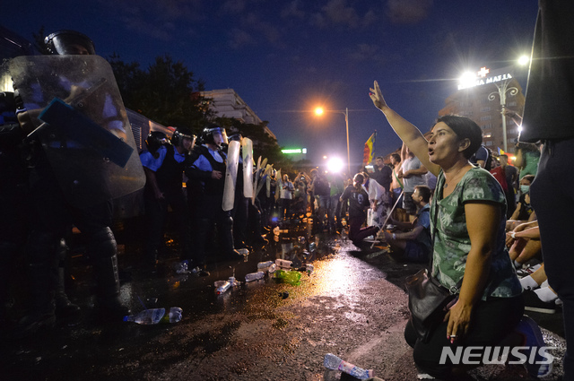 【부쿠레슈티(루마니아)=AP/뉴시스】루마니아 수도 부쿠레슈티의 정부청사 앞에서 10일 내각 사퇴를 요구하는 반정부시위를 벌이는 한 여성 시위대원이 진압경찰에 맞서 구호를 외치고 있다. 경찰이 무력 진압에 나서면서 경찰 30여명을 포함해 455명이 부상을 입었다. 그러나 생명이 위험한 사람은 없다고 경찰은 말했다. 2018.8.11