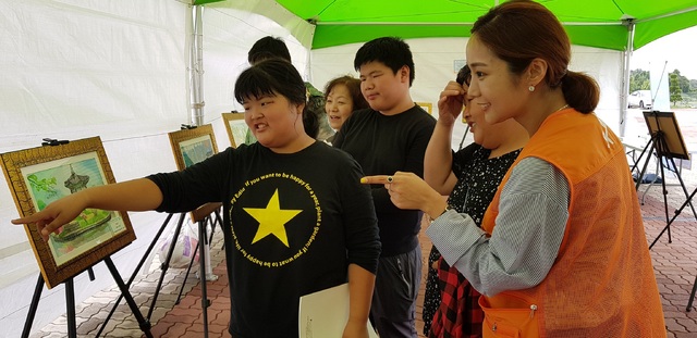 ‘2018 SK지크 레이싱 페스티벌’에 방문한 발달장애인과 가족들이 SK이노베이션 자원봉사자의 인솔 하에 전시된 그림들을 구경하고 있다. 