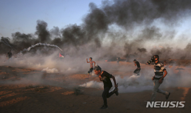 【가자지구 = AP/뉴시스】가자지구 국경에서 10월 12일 이스라엘군의 사격에 맞서서 돌팔매를 던지고 있는 팔레스타인 시위대. 이스라엘군은 1만 4000여명의 시위대가 국경지대에서 이스라엘군에게 돌과 화염병을 던지며 타이어를 불태웠다고 주장했다.  
