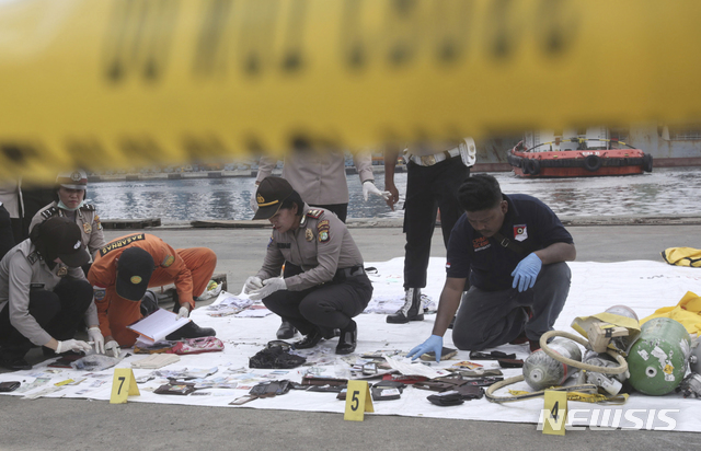 【자카르타=AP/뉴시스】인도네시아 경찰들이 30일 자카르타 항구에서 라이온에어 여객기 추락 희생자들의 소지품으로 보이는 물건들을 조사하고 있다. 2018.10.30