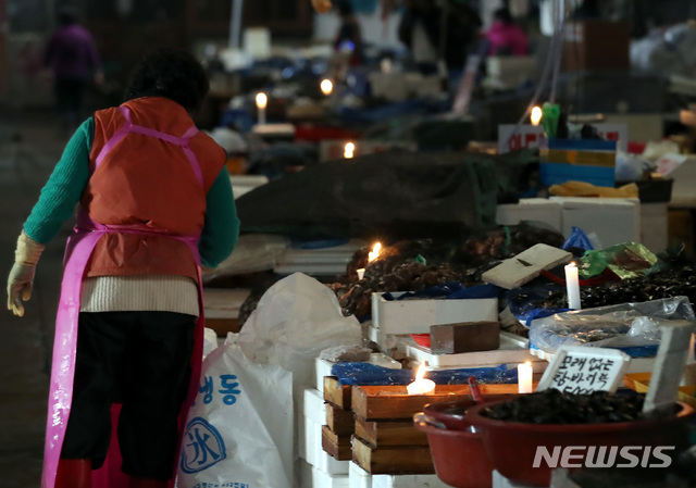 【서울=뉴시스】이영환 기자 = 수협이 노량진 수산시장 구시장 전역에 단전과 단수를 진행한지 하루 지난 6일 오전 서울 동작구 노량진 수산시장 구시장이 어둑어둑한 가운데 상인들이 촛불을 켜고 장사를 하고 있다. 2018.11.06.  20hwan@newsis.com