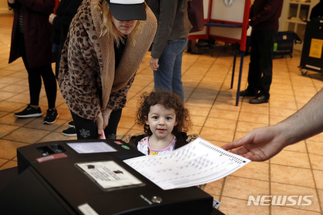 6일 뉴욕주 마운티 키스코의 투표소, 광학스캔 방식으로 부스에서 기표한 투표지를 엄마가 스캔해서 선거본부에 보내는 것을 아이가 보고 있다  AP
