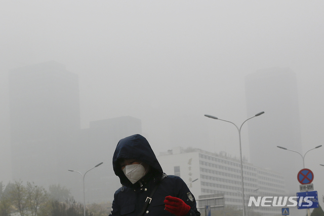 【베이징=AP/뉴시스】14일 중국 베이징 도심에서 한 시민이 마스크를 착용하고 걸어가고 있다. 이날 베이징은 올 겨울 들어 첫 번째 심각한 스모그로 비상에 걸렸다. 2018.11.14 