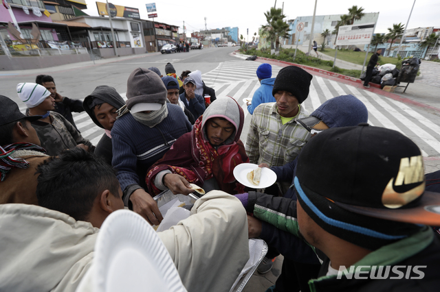 【티후아나(멕시코)= AP/뉴시스】티후아나의 미국 국경에 도착한 이민들에게 한 자원봉사자가 14일 (현지시간) 손수 만든 타코를 나눠주고 있다. 이민들은 트럭과 버스를 제공받아 하루 수백마일씩 빠른 속도로 이동해 이미 선두의 수백명이 이 곳에 도착했다. 