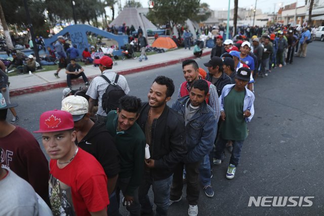 【멕시칼리(멕시코)=AP/뉴시스】미국으로 향하는 중미 이주자들이 19일 멕시코 멕시칼리에서 무료로 제공되는 저녁식사를 받기 위해 길게 줄을 서 순서를 기다리고 있다. 미 법원은 이날 불법으로 국경을 넘은 사람들의 망명 신청을 거부하라는 도널드 트럼프 대통령의 행정명령의 이행을 금지시켰다. 2018.11.20