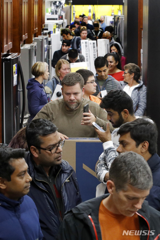 People line up to pay for their purchases as they shop during an early Black Friday sale at a Best Buy store on Thanksgiving Day Thursday, Nov. 22, 2018, in Overland Park, Kan. (AP Photo/Charlie Riedel)