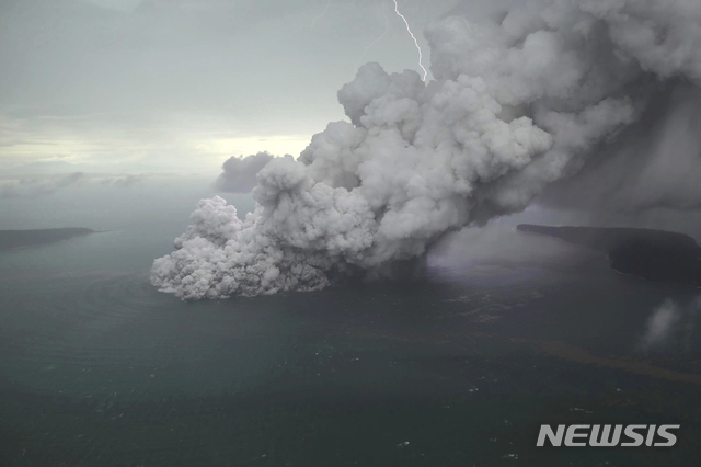 【AP/뉴시스】 인도네시아 순다 해협에 위치한 아낙 크라카타우 화산에서 23일 검은 연기와 화산재가 뿜어져 나오고 있다. 이 화산은 전날 폭발하면서 거대한 쓰나미를 일으켜 막대한 인명피해를 초래했다. 2018.12.25  