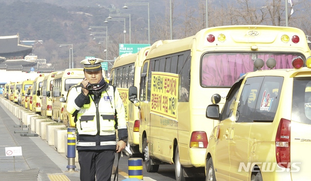 【서울=뉴시스】최진석 기자 = 지난해 12월31일 서울 종로구 세종대로에서 한국유치원총연합회(한유총) 소속 유치원 버스에 자신들이 요구하는 메시지를 붙이고 한 차로에서 떼 지어 저속주행을 하자 경찰이 유치원 버스를 촬영하고 있다. 2018.12.31. myjs@newsis.com