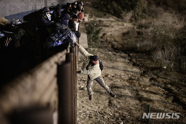 【티후아나(멕시코)= AP/뉴시스】미국과 멕시코 국경 울타리 아래 땅굴을 파 입국한 이주민 375명이 구금됐다고 CNN이 18일 보도했다. 사진은 지난 1일 멕시코 티후아나 국경선에서 한 이주민이 미국 샌디에이고 쪽으로 뛰어내리는 모습. 2019.01.18.