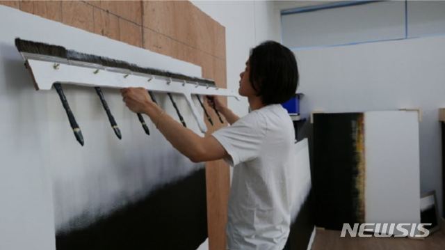 【서울=뉴시스】 박현주 미술전문기자 = 김수수 작가가 대형 붓 6개를 묶어 만들어 화면에 물감을 한번에 쓸어내리는 작업을 하고 있다. 