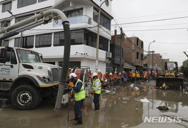 【리마(페루)=AP/뉴시스】페루의 수도 리마 시 직원들이 16일(현지시간 ) 하수가 넘쳐 악취가 진동하는 산후안 데 루리간초 구에서 오폐수를 퍼내고 있다. 
