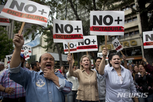 People holding signs with a message that reads in Spanish: &quot;No more dictatorship&quot; take part in a walkout against President Nicolas Maduro, in Caracas, Venezuela, Wednesday, Jan. 30, 2019. Doctors in scrubs, businessmen in suits and construction workers in jeans gathered on the streets of Venezuela&#039;s capital Wednesday, demanding Maduro step down from power in a walkout organized by the nation&#039;s reinvigorated opposition to ratchet up pressure on the embattled president. (AP Photo/Ariana Cubillos)