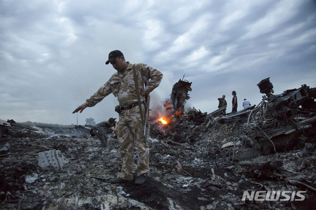 【AP/뉴시스】 2014년 7월 17일 우크라이나 그라보보 인근에서 친러 반군의 미사일 공격으로 격추당한 말레이시아 여객기의 잔해를 구조대가 조사하고 있다.  