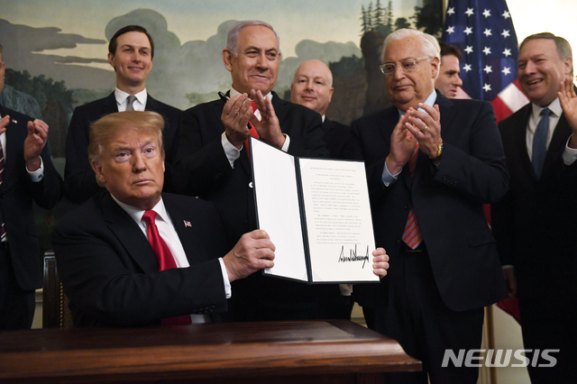 【워싱턴=AP/뉴시스】도널드 트럼프 미국 대통령이 25일(현지시간) 백악관에서 베냐민 네타냐후 이스라엘 총리 등이 지켜보는 가운데 시리아 골란고원에 대한 이스라엘의 주권을 인정하는 포고문(proclamation)에 서명하고 사람들에게 보여주고 있다. 2019.03.26 