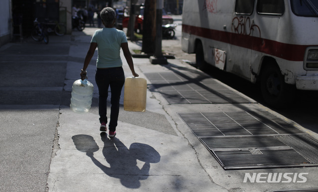 【카라카스=AP/뉴시스】베네수엘라에 정전으로 수도마저 끊겨 지난달 26일(현지시간) 수도 카라카스에서 한 여성이 빈 물통을 들고 물탱크가 있는 한 애완동물 상점으로 물을 구하러 가고 있다.  베네수엘라 전역에 정전이 재발, 확산하면서 수많은 사람이 전기와 수도가 끊어진 채 불편을 감수하고 있다. 2019.03.27.