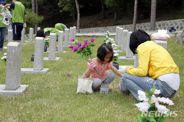 한국전쟁 전사자들이 안장된 현충원 48번 묘역에서 지난 18일 봉사활동 중인 현대엔지니어링 임직원 가족.(사진제공=현대엔지니어링)