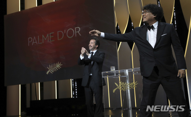 Director Bong Joon-ho, right, accepts the Palme d'Or award for the film 'Parasite' during the awards ceremony at the 72nd international film festival, Cannes, southern France, Saturday, May 25, 2019. (Photo by Vianney Le Caer/Invision/AP) 