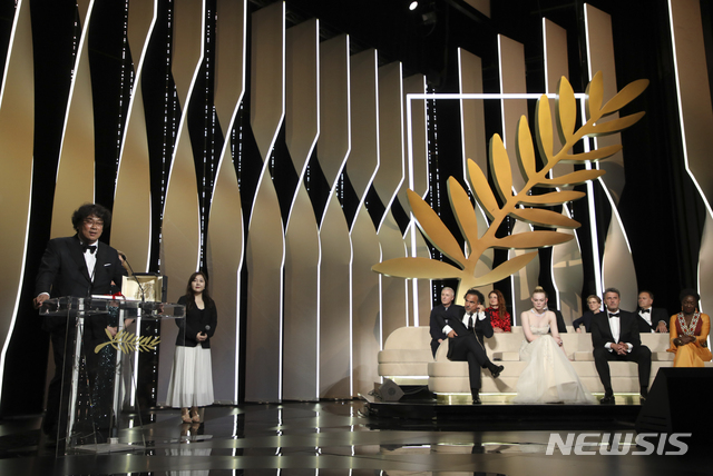 Director Bong Joon-ho, left, accepts the Palme d'Or award for the film 'Parasite' as members of the jury Robin Campillo, from back right Alice Rohrwacher, Kelly Reichardt, Enki Bilal, jury president Alejandro Gonzalez Inarritu, from bottom right, jury members Elle Fanning, Pawel Pawlikowski and Maimouna N'Diaye look on during the awards ceremony at the 72nd international film festival, Cannes, southern France, Saturday, May 25, 2019. (Photo by Vianney Le Caer/Invision/AP)