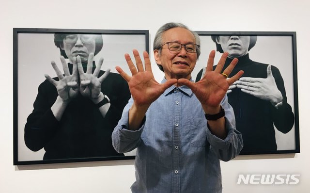 【서울=뉴시스】박현주 미술전문기자= 이건용이 1975년부터 1980년도에 펼친 손을 이용한 퍼포먼스를 당시 흑백 사진앞에서 재현하고 있다.