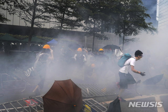 【홍콩=AP/뉴시스】홍콩 입법원 근처에서 12일 범죄인 인도법 반대 시위참가자들이 경찰이 쏜 최루가스를 피하고 있다. 2019.06.12 