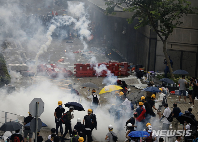 【홍콩=AP/뉴시스】홍콩 경찰들이 12일 입법원 근처 도로에서 범죄인 인도법 반대 시위대를 향해 최루탄을 쏘고 있다.2019.06.12 