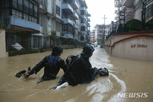 12일 네팔 수도 카트만두에서 거리가 물에 잠긴 가운데 주민이 오토바이를 끌면서 헤쳐가고 있다  AP 