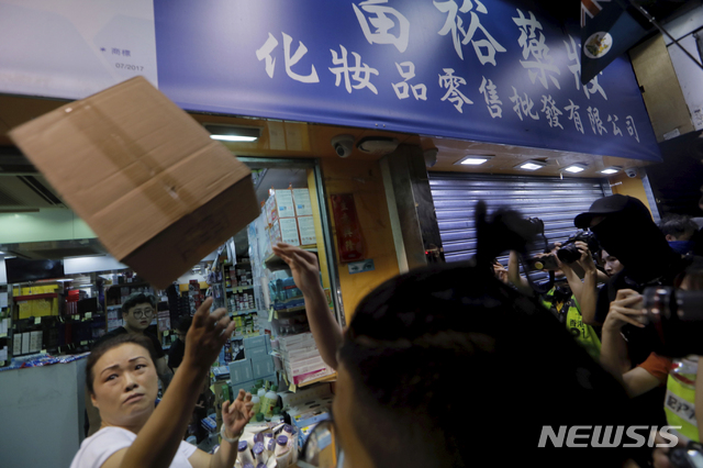 【홍콩=AP/뉴시스】13일(현지시간) 한 상점 주인이 홍콩 시위대가 던진 종이박스를 막으려고 하고 있다. 홍콩 시위대 수천명은 이날 중국 본토 선전과 가까운 셩수이 지역에서 중국 본토와 거래하는 보따리 상인들에 반대하는 시위를 벌였다. 2019.07.14