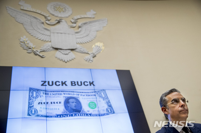 Facebook CEO Mark Zuckerberg&#039;s face is visible on a mock &quot;Zuck Buck&quot; depicted on a screen behind David Marcus, CEO of Facebook&#039;s Calibra digital wallet service, as he is questioned by Rep. Brad Sherman, D-Calif., during a House Financial Services Committee hearing on Facebook&#039;s proposed cryptocurrency on Capitol Hill in Washington, Wednesday, July 17, 2019. (AP Photo/Andrew Harnik)