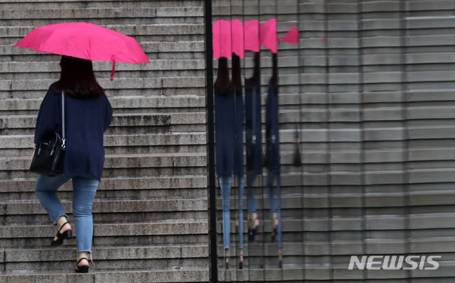 【서울=뉴시스】홍효식 기자 = 장마전선 유입으로 전국 대부분이 흐리고 비가 내리는 25일 오후 서울 종로구 세종문화회관 계단에서 한 시민이 우산을 쓴 채 발걸음을 옮기고 있다. 2019.07.25.  yesphoto@newsis.com 