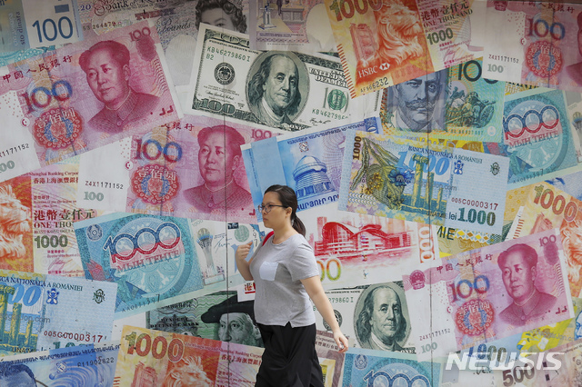 【홍콩=AP/뉴시스】6일 홍콩에서 한 여성이 달러와 위안화 등으로 장식된 환전소 앞을 지나고 있다. 2019.08.06. 