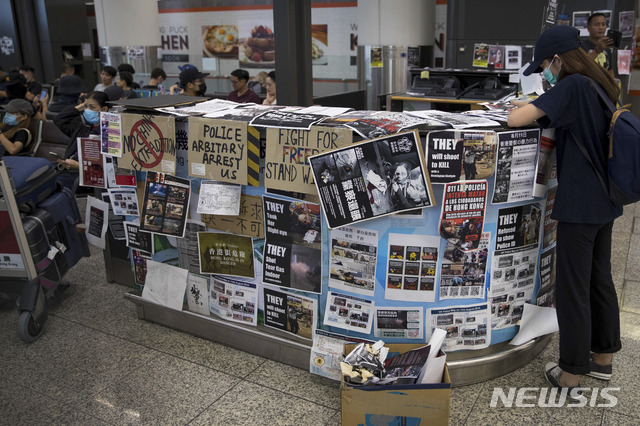 【홍콩=AP/뉴시스】홍콩 시위대의 점거로 항공 운항이 중단된 홍콩 국제공항에서 12일(현지시간) 한 여행객이 시위대의 전단지가 붙어있는 안내대에서 스마트폰을 검색하고 있다. 수천 명의 시위대가 공항 입국장에 몰려들어 12일 항공기 운항을 중단했던 홍콩 국제공항은 13일 오전 운항을 재개했다고 밝혔다. 2019.08.13.