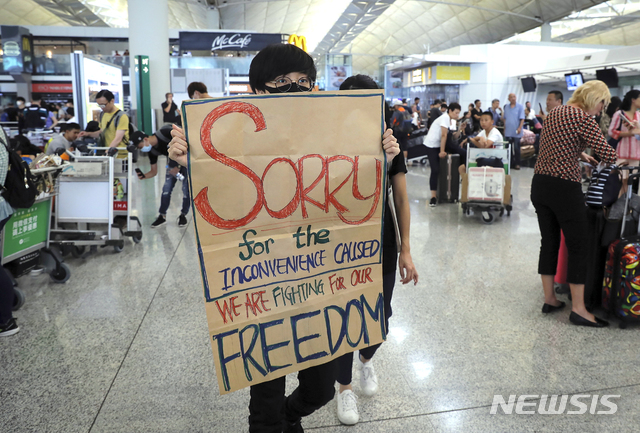 【홍콩=AP/뉴시스】13일(이하 현지시간) 홍콩 국제공항에서 한 시위대가 불편을 겪고 있는 여행자들에게 "불편을 줘서 미안하다, 자유를 위해 투쟁 중이다"라는 팻말을 들고 걷고 있다. 홍콩 국제공항 측은 수천 명의 시위대가 다시 터미널 출입국장을 점거해 오후 4시30분 기준으로 항공사 체크인 업무를 전면 중단한다고 발표했다.그때까지 체크인을 완료한 출발 항공편은 예정대로 이륙하지만 체크인이 진행 중인 항공기도 그 시각부터 업무를 중단해 항공기 운항이 취소됐다. 2019.08.13.