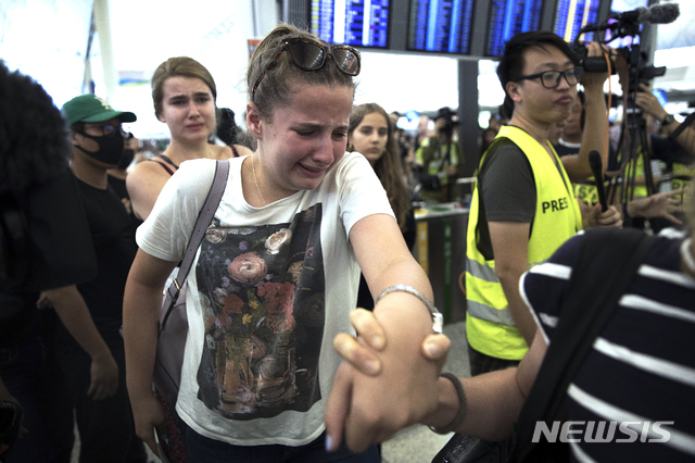  【홍콩=AP/뉴시스】13일(이하 현지시간) 홍콩 국제공항에서 가까스로 시위대를 통과해 출국장으로 향하는 한 여행객이 울음을 터트리고 있다.  홍콩 국제공항 측은 수천 명의 시위대가 다시 터미널 출입국장을 점거해 오후 4시30분 기준으로 항공사 체크인 업무를 전면 중단한다고 발표했다. 그때까지 체크인을 완료한 출발 항공편은 예정대로 이륙하지만 체크인이 진행 중인 항공기도 그 시각부터 업무를 중단해 항공기 운항이 취소됐다. 2019.08.13. 