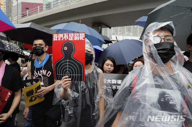 【홍콩=AP/뉴시스】18일 대규모 반정부 시위가 예고된 홍콩에서 시위대 원들이 '우리는 공격 표적이 아니다'라고 적힌 손팻말을 들고 행진하고 있다. 이날 대규모 시위가 예정된 가운데 인근 선전(深圳)에서 중국 무장 공안이 훈련을 벌이며 무력 시위를 했다. 2019.8.18