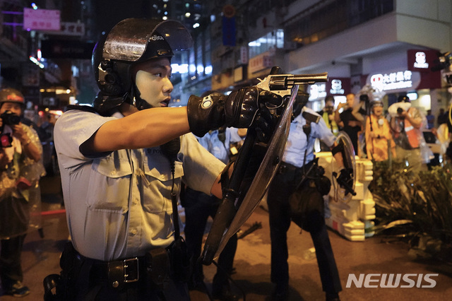 【홍콩=AP/뉴시스】25일 홍콩 도심에서 한 경찰관이 시위대를 향해 총을 겨누고 있다. 범죄인 인도법(송환법) 반대 12번째 주말 집회가 이날 열린 가운데 시위대로부터 생명의 위협을 느낀 한 경찰관이 경고로 공중에 실탄 사격을 한 것으로 알려졌다. 2019.08.26 