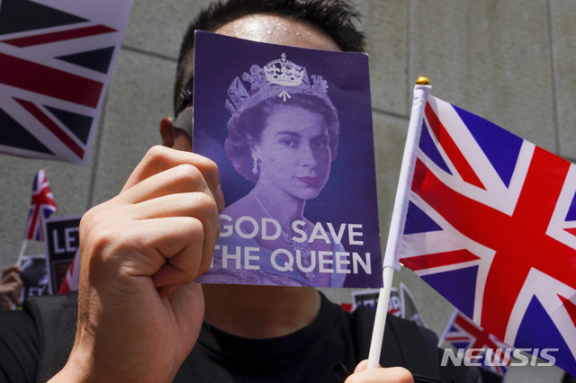 【홍콩=AP/뉴시스】14일 홍콩 영국총영사관 밖에서 열린 시위에서 한 참가자가 '여왕 폐하 만세'라고 적힌 카드와 유니언잭을 흔들고 있다. 이들은 이들은 과거 식민지 지배국가였던 영국이 지난 1984년 서명한 홍콩반환협정에 따라 중국이 홍콩 자유, 자치권에 대한 약속을 지키도록 촉구할 것을 요구했다. 2019.09.15. 