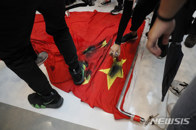 【홍콩=AP/뉴시스】22일 홍콩 샤틴역 인근 쇼핑몰에서 범죄인 인도법(송환법) 반대 시위대가 중국 국기 오성홍기를 밟고 검은 스프레이를 뿌리고 있다. 2019.09.23 