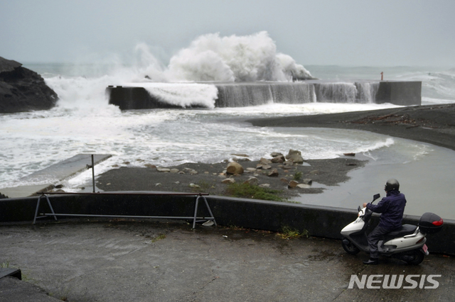 【구마노=AP/뉴시스】지난 12일 일본 미에현 구마노 해변에 제19호 태풍 하기비스의 영향으로 거센 파도가 방파제를 덮치는 모습을 한 남성이 스쿠터에 앉아 바라보고 있다. 2019.10.12. 