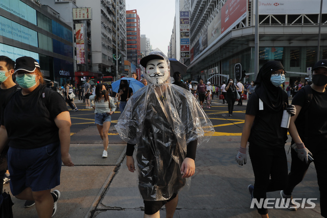 【홍콩=AP/뉴시스】가면과 마스크로 얼굴을 가린 홍콩 시민들이 12일 시내 중심가에서 행진하고 있다. 2019.11.13 