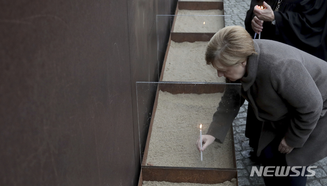 【베를린=AP/뉴시스】9일(현지시간) 독일 베를린에서 열린 '베를린 장벽 붕괴 30주년' 기념식에서 앙겔라 메르켈 총리가 촛불을 밝히가 있다. 이는 베를린 장벽을 넘어 서베를린으로 탈출하려다 동독 경비병의 총격에 숨진 동독 시민들을 추모하기 위한 것이다. 2019.11.09