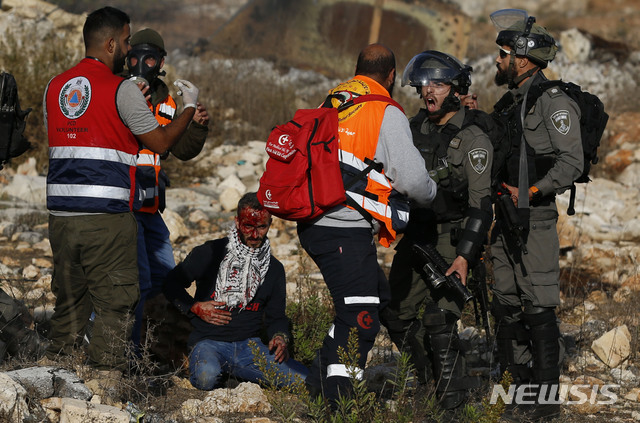 【서안지구=AP/뉴시스】지난 16일(현지시간) 요르단강 서안지구 라말라 인근 베이엘 검문소에서 한 팔레스타인 남성이 이스라엘의 가자지구 공습에 항의하는 시위대에 참가했다가 이스라엘 보안군에 의해 부상을 입고 피를 흘리고 있다. 팔레스타인 구급대원들이 남성을 치료하고자 접근하려 했지만 보안군에 제지당했다. 2019.11.21
