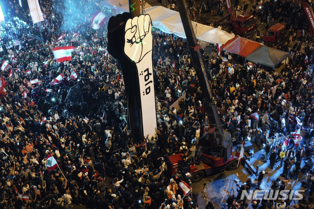 [베이루트( 레바논)= AP/뉴시스] 레바논의 반정부 시위대가 22일(현지시간) 정부 각료들의 퇴진을 요구하면서 베이루트 시내의 '순례자의 광장'에 모여서 "혁명"이라고 쓴 거대한 마분지 주먹을 세워놓고 있다.  